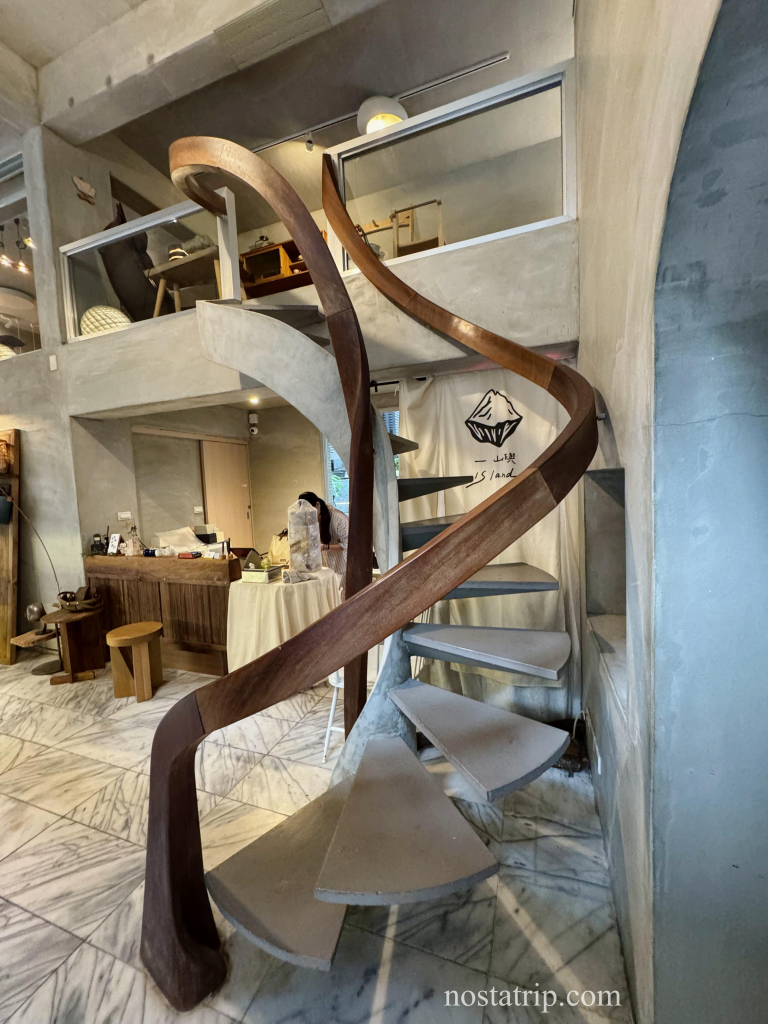 一嶼 Island 室內空間中的旋轉樓梯，以木質扶手與灰白階梯交織而成，帶出空間的柔和律動感