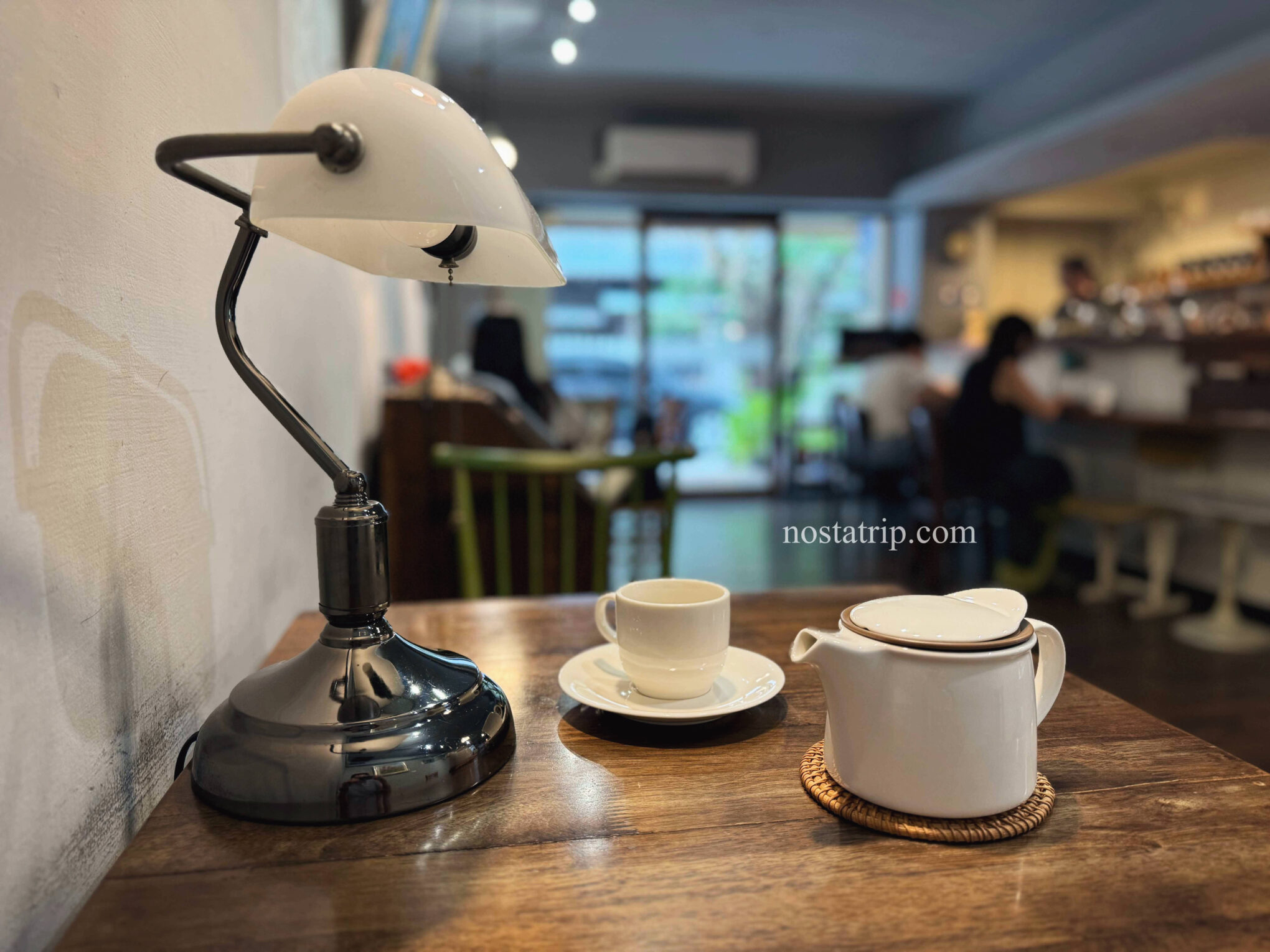貳月咖啡店內桌景，檯燈、白瓷壺與茶杯靜靜擺放，背景為溫暖安靜的懷舊空間。
