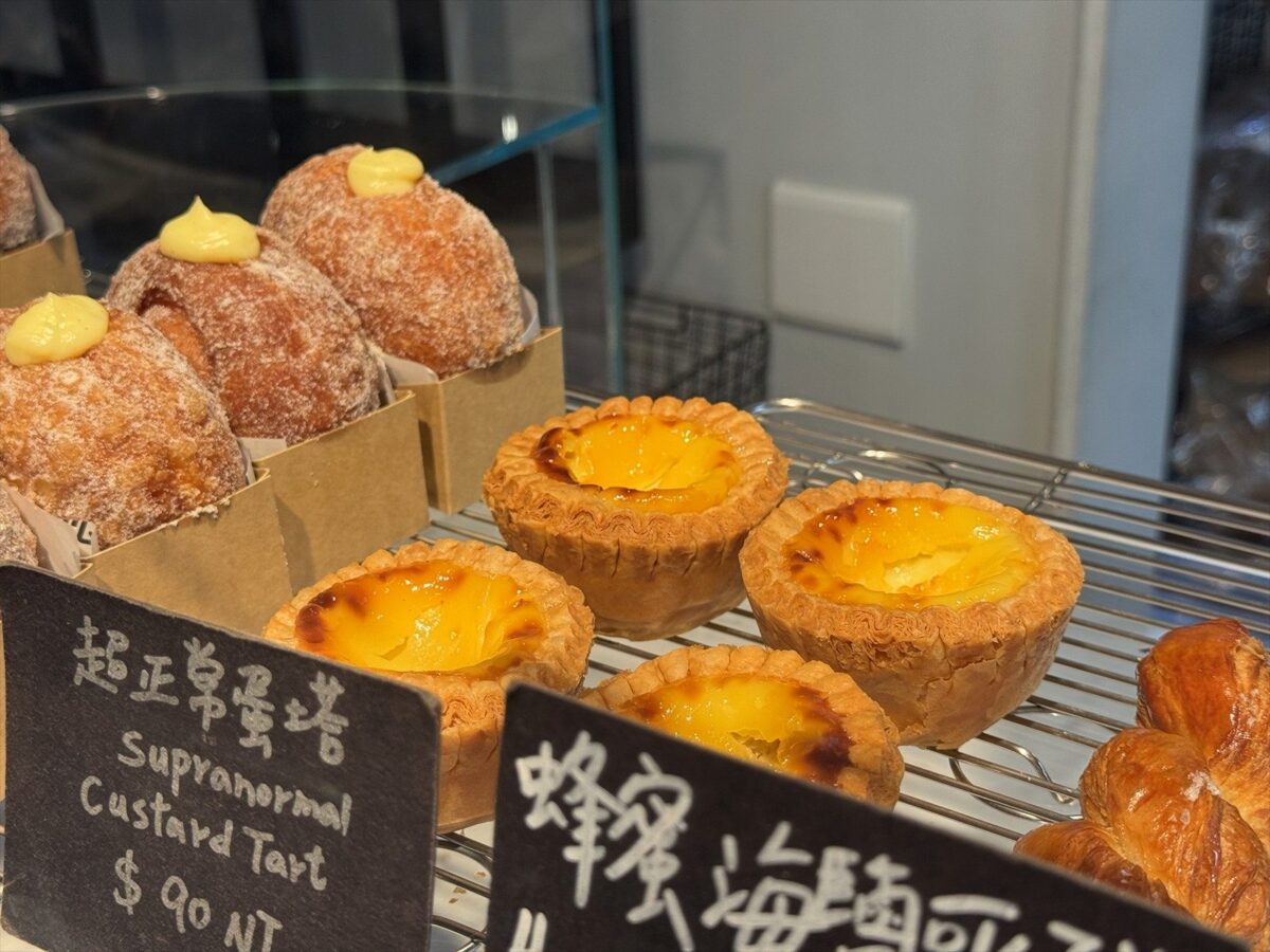 Supranormal Bakery Café 展示架上的麵包、卡士達蛋塔與手寫價牌