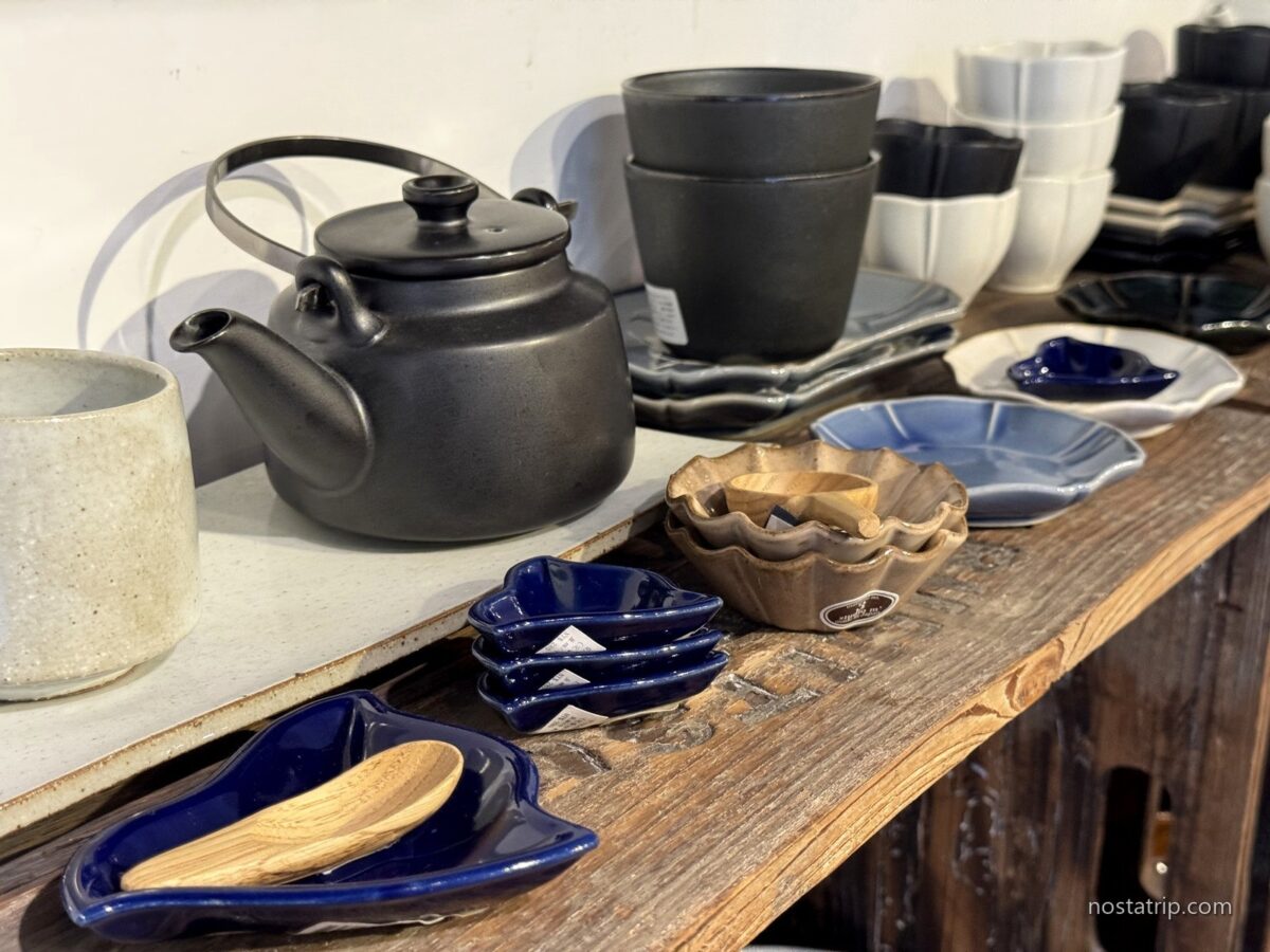 小器生活赤峰28店木桌上的黑色陶壺、杯盤與藍色器皿